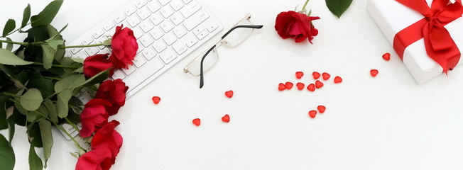 Banner flat lay,  top view Valentine's day women's office desk. Female workspace with laptop,  flowers red roses,  accessories, glasses, gift on white  background. feminine background.Copy space