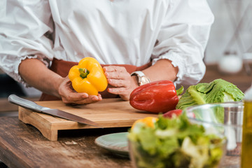 cropped image of woman preparing salad for dinner and holding bell pepper at home