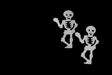 Halloween concept: grey skeletons, black background, free copy space