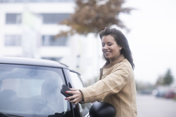 Junge Frau mit Smartphone checkt Carsharing Auto