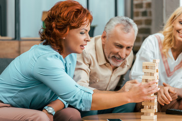 beautiful mature woman playing with wooden blocks while spending time with old friends at home