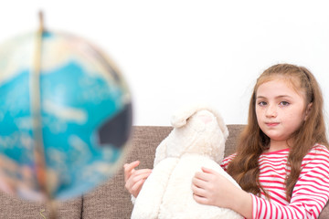Little girl playing with doll and map Globe
