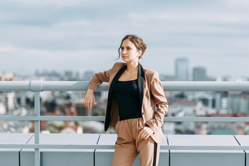 Obraz premium Stylish young business girl. In the city and on the roof. Views and business style. In a hurry and sitting waiting for a meeting.