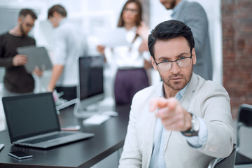 successful businessman sitting at his Desk and pointing at you