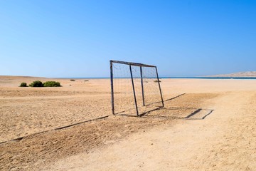 Soccer goal in the sand on the beach in front of blue sky