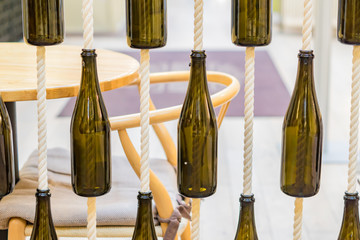 interior decorative elements -dark glass empty bottles hanging on rope, background