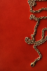 Fototapeta na wymiar Gold chain on reddish brown leather background.