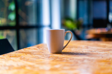 White coffee or tea mug on a textured desk near a window