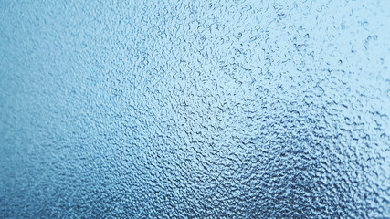 Frozen winter glass or window, abstract blue background.