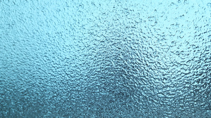 Frozen winter glass or window, abstract blue background.