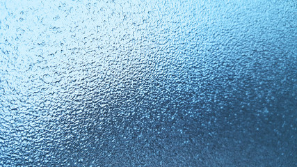 Frozen winter glass or window, abstract blue background.