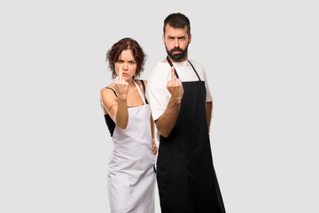 Couple of cooks making horn gesture. Negative expression on grey background