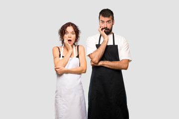 Couple of cooks surprised and shocked while looking right on grey background