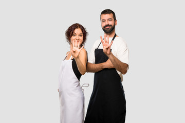 Couple of cooks happy and counting four with fingers on grey background