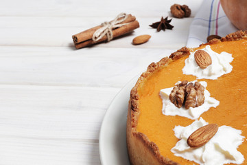 Copy space. Closeup of pumpkin pie with whipped cream. Nuts and pumpkin. Pumpkin pie on a white wooden table. Ingredients for cooking pumpkin pie. Place for text. Flat laу
