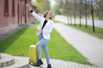 beautiful caucasian girl with long hair holding a big yellow suitcase. Concept - travel tourism