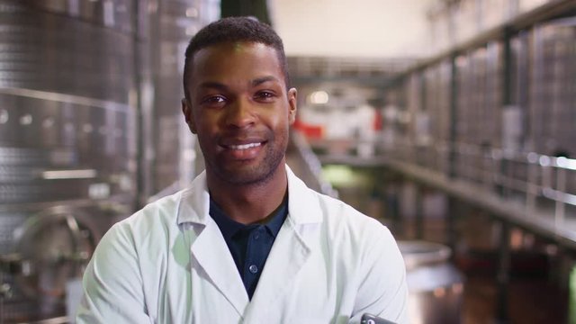 Young black man working at a wine factory walking into focus