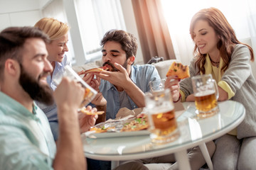 Group of friends enjoying pizza and beer