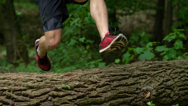 the guy jumps over a large log while participating in an ocr race