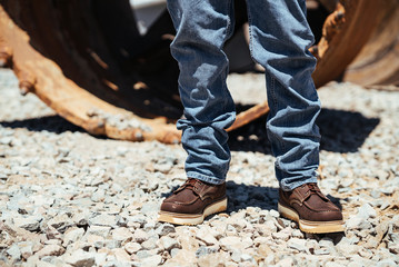 Man Stands on Construction Site in Work Boots