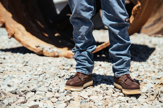 Man Stands On Construction Site In Work Boots