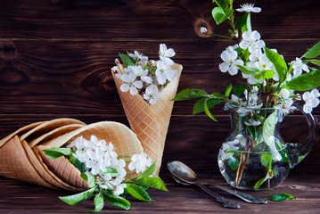 Fresh flowers in ice cream cone still life on a dark wooden background