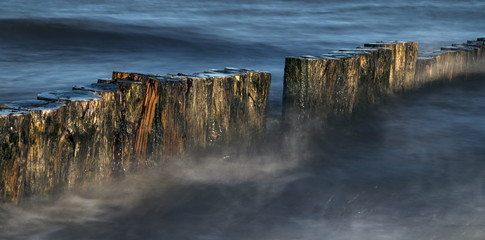 wooden groynes in the blue sea, smooth water by long exposure, nature background with copy space in...