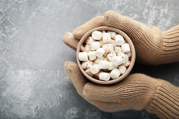 Female hands holding cup of cappuccino with marshmallow