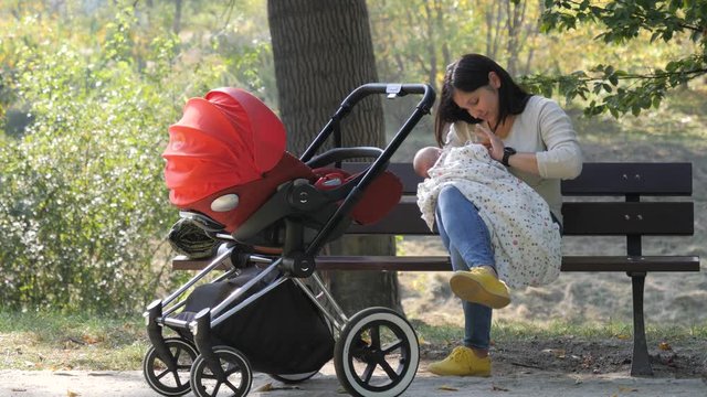 Young mother breastfeeds the baby on a park bench in a public place