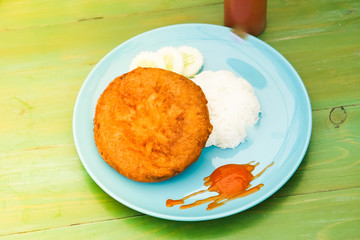 Steamed rice with minced pork and fluffy omelet in a dish put on the green table.