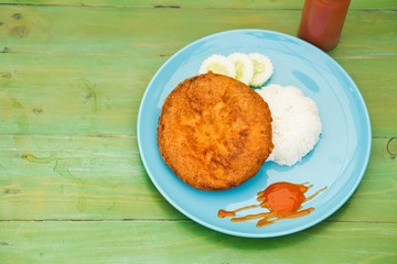 Steamed rice with minced pork and fluffy omelet in a dish put on the green table.
