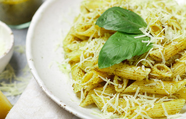 Penne pasta with pesto sauce, Parmesan cheese, olive oil and Basil. Delicious traditional dinner or lunch in Mediterranean (italian) style. Selective focus