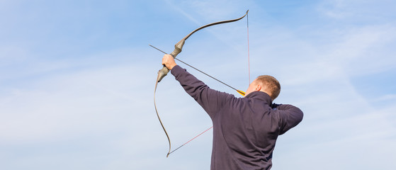 Athlete aiming at a target and shoots an arrow. Archery. Banner