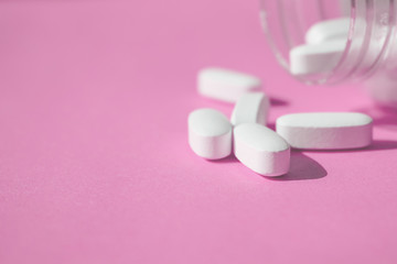 Placebo pills, fake medical treatment. Close up white pills with bottle on pink background.