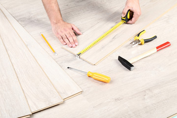 Fototapeta na wymiar Man installing timber laminate flooring with tools