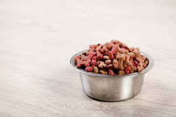 Dry pet food in bowl on timber flooring at home