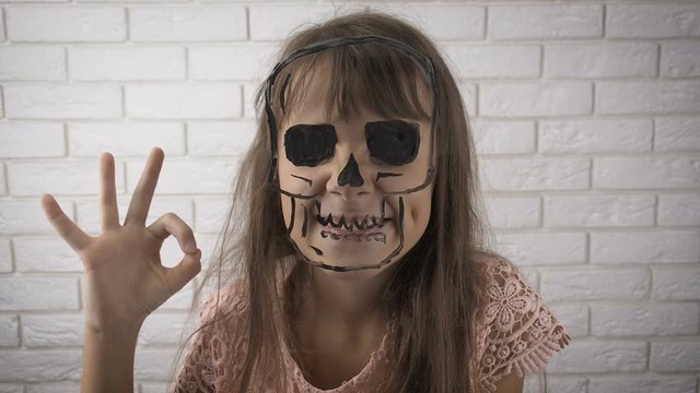 Halloween Figure skull. Painted skull on the glass. The girl hides face behind the skull.