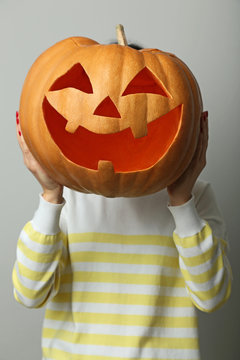 Female hands holding halloween pumpkin on grey background