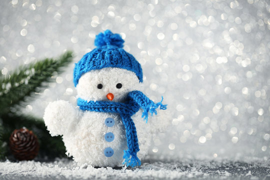 Small snowman toy with fir-tree branches on lights background