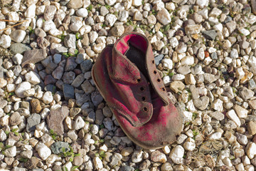 Fototapeta premium Old, red children's boot on a gravel road