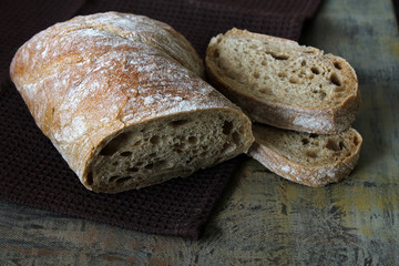 Ciabatta. Traditional Italian bread with two slices of bread placed on top of each other on the brown towel.