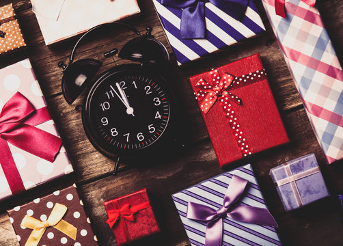 colorful gifts and black clock on the brown wooden table