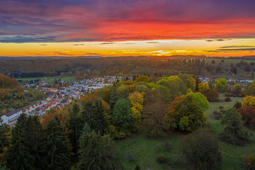 Ein farbenfroher Sonnenuntergang aus der Luft via Drohne aufgenommen im letzten Herbstlicht mit bunten B&auml;umen &uuml;ber der Schw&auml;bischen Alb
