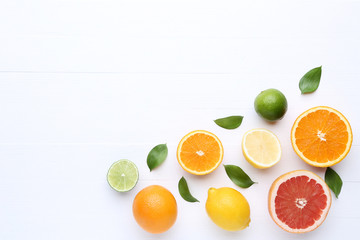 Fototapeta na wymiar Citrus fruits with green leafs on white wooden table