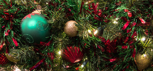 Festive Holiday Background. Christmas tree decorated with ornaments and illuminated with multi colored lights in panoramic orientation.