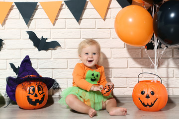 Baby girl in halloween costume with pumpkin buckets and balloons