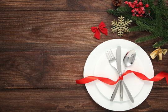 Kitchen cutlery in white plate and christmas decorations on wooden table
