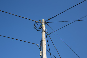 Wooden electric pole on blue sky background
