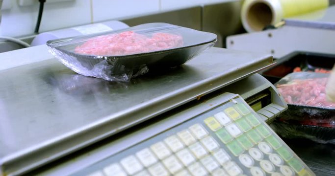 Butcher weighing minced on weighing machine in butchers shop 4k