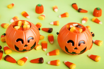 Halloween candy corns in pumpkin buckets on green background
